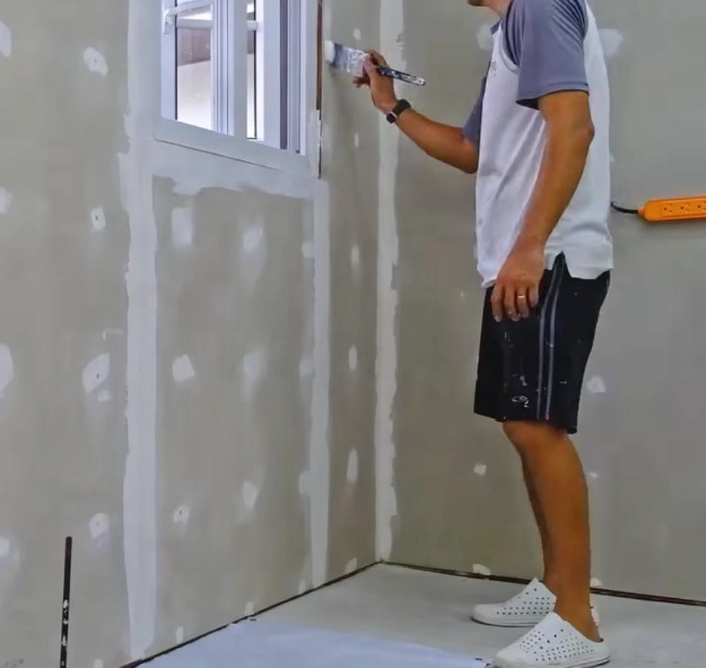 Painter applying acrylic latex coating to fiber cement siding